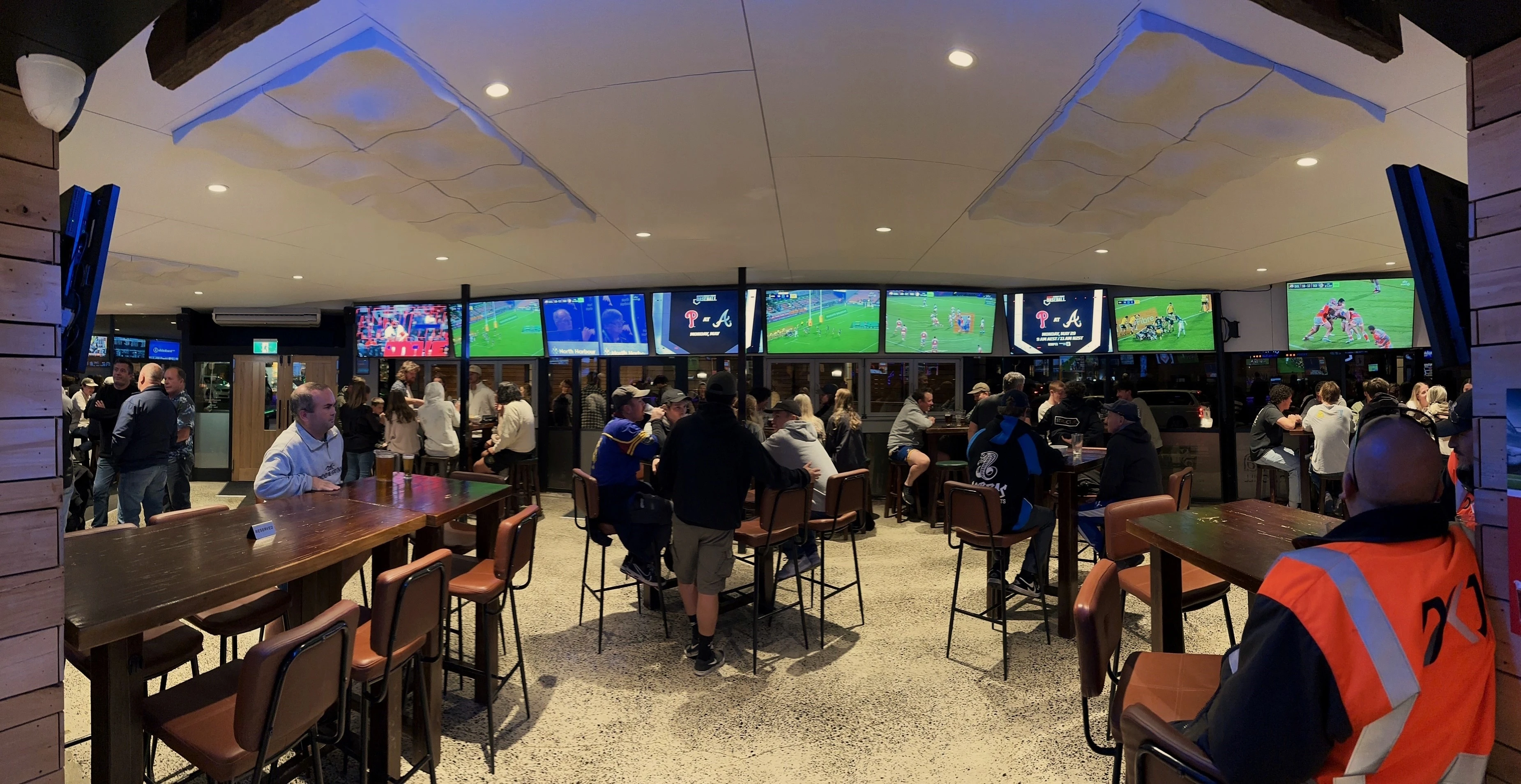 A lively night at The Baaa with patrons watching sport across the bar televisions
