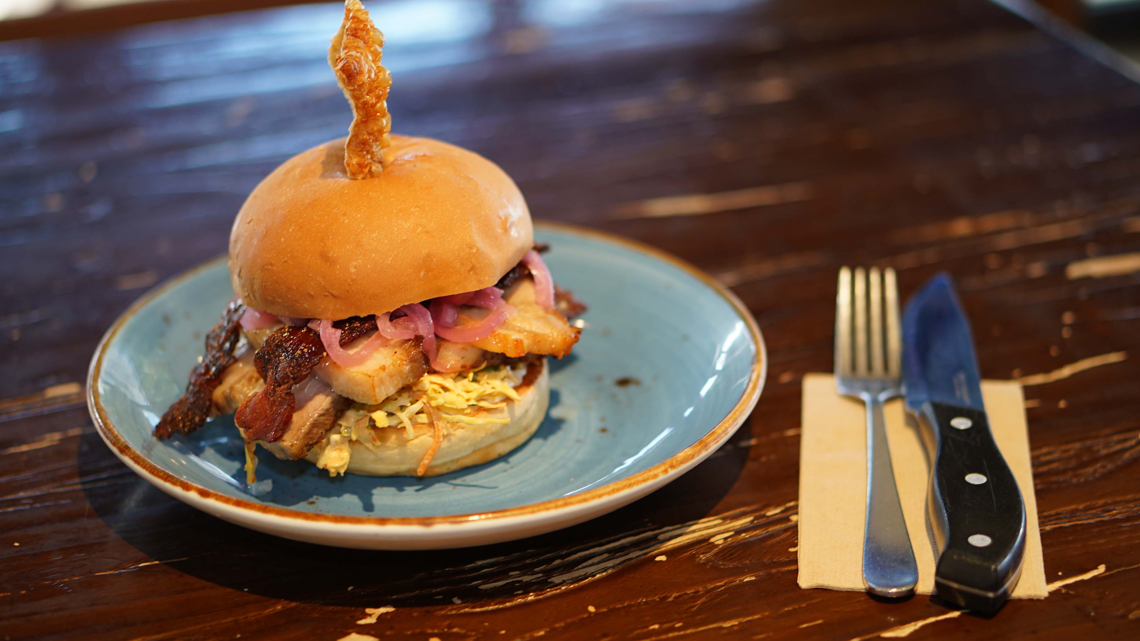 A stacked pork burger served on a blue plate